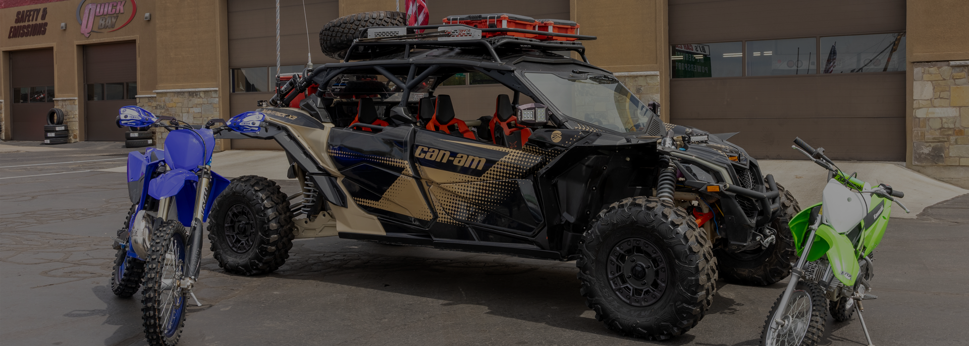 Off-road dune buggy with blue and green ATVs parked outside a garage | BJ's Car Care