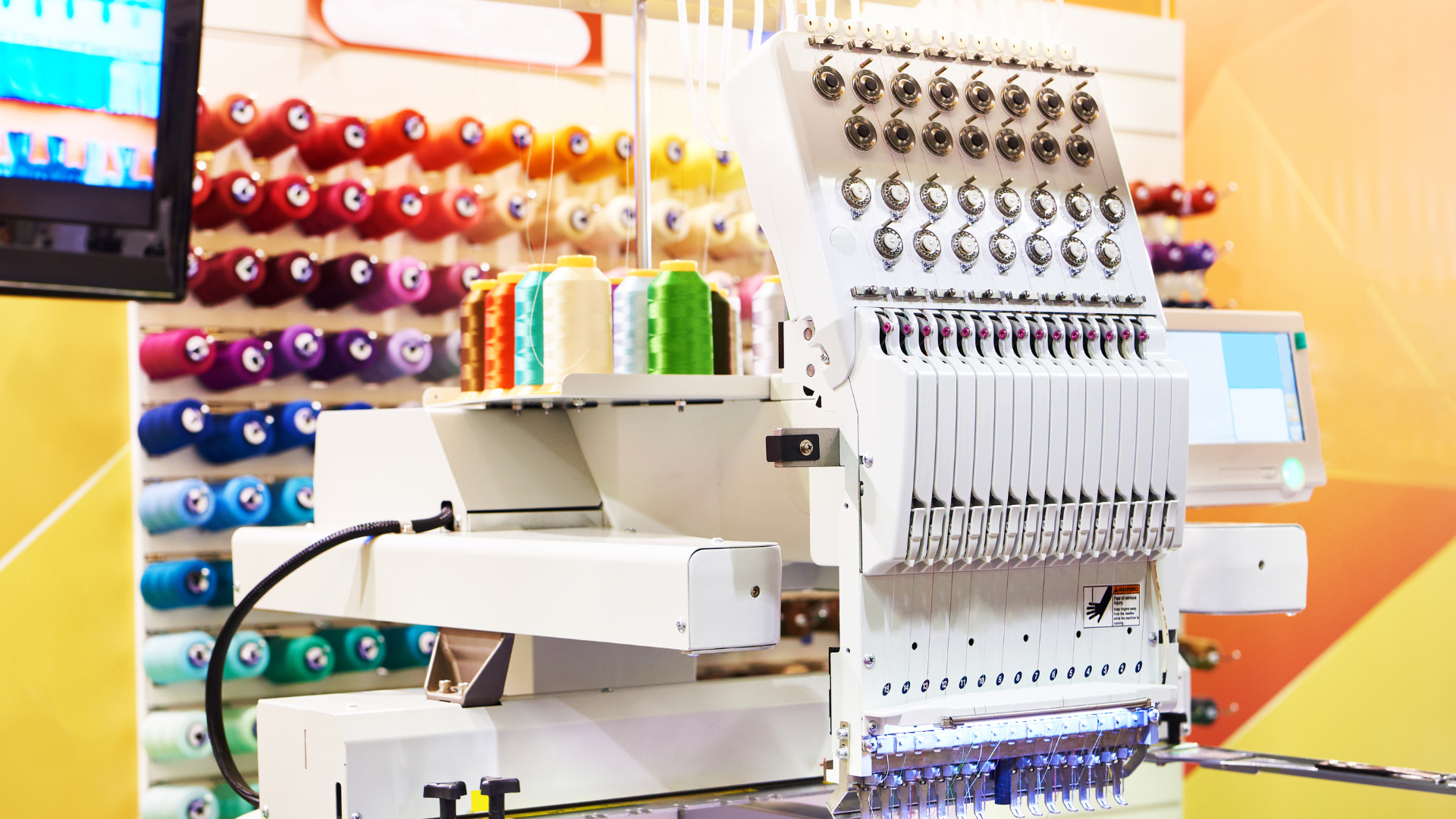 Embroidery machine with multiple thread spools in various colors.