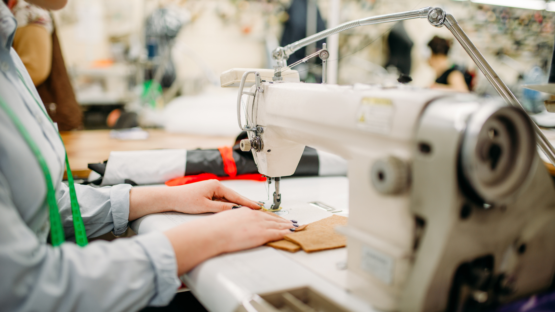Person sewing at a white industrial sewing machine in a workshop.