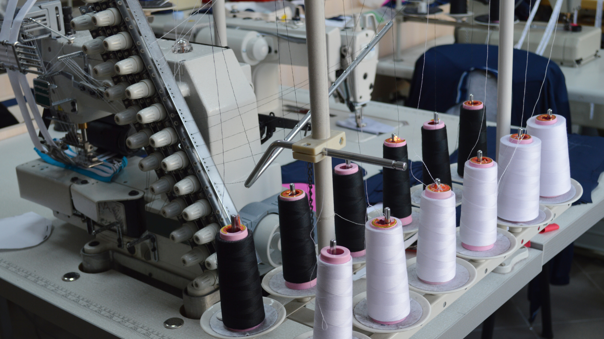 Sewing machines with spools of black and white thread on a work table.