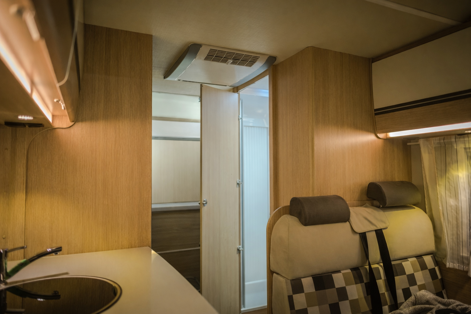 Interior of An Rv Featuring a Kitchen Counter on The Left, a Doorway to A Bathroom, and Cushioned Seating on The Right — Elite Fleet Auto - Electrics & Mechanical in Cannonvale, Qld