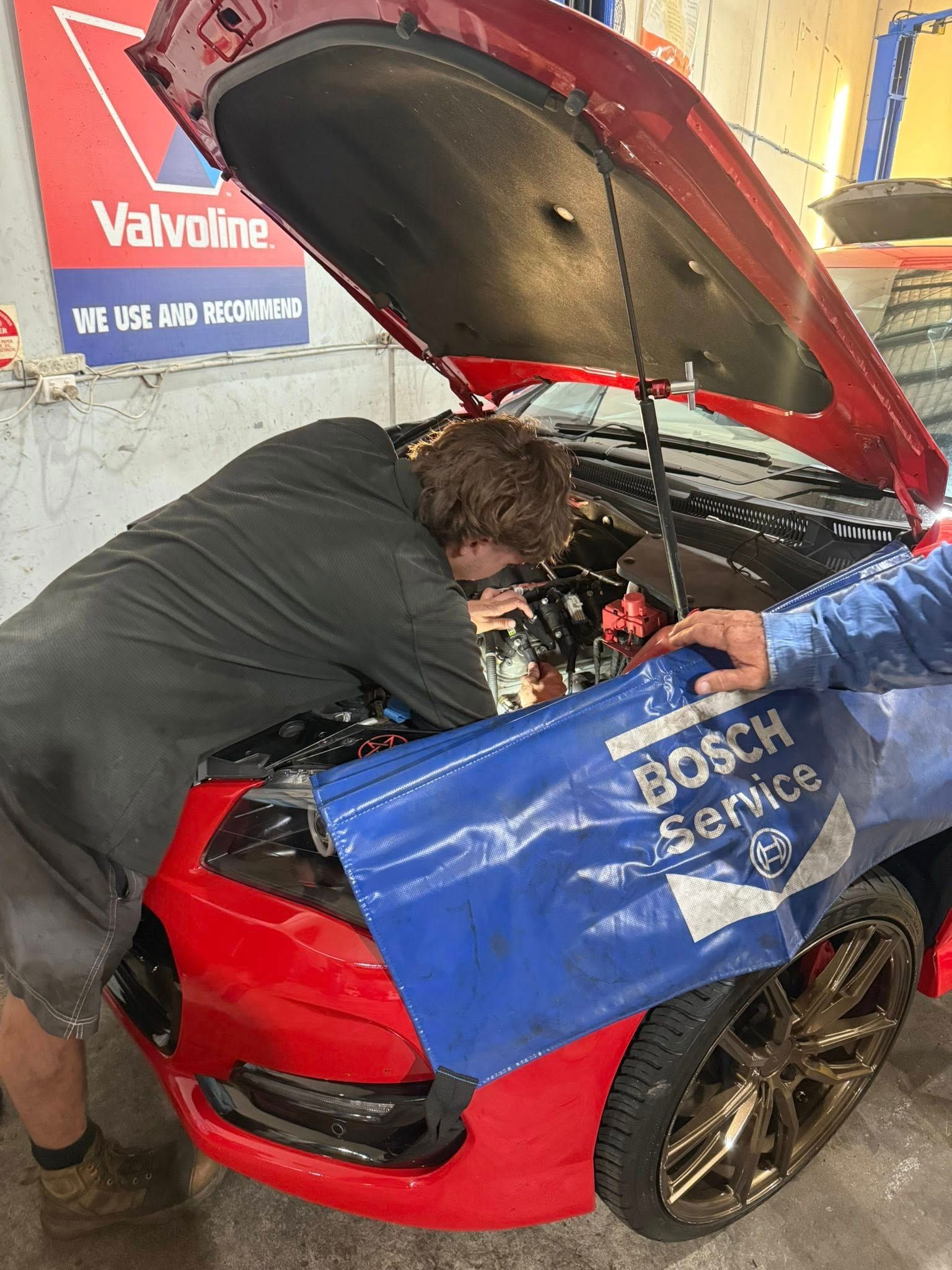 Mechanic Working Under the Hood of A Red Car in A Garage — Elite Fleet Auto - Electrics & Mechanical in Cannonvale, Qld