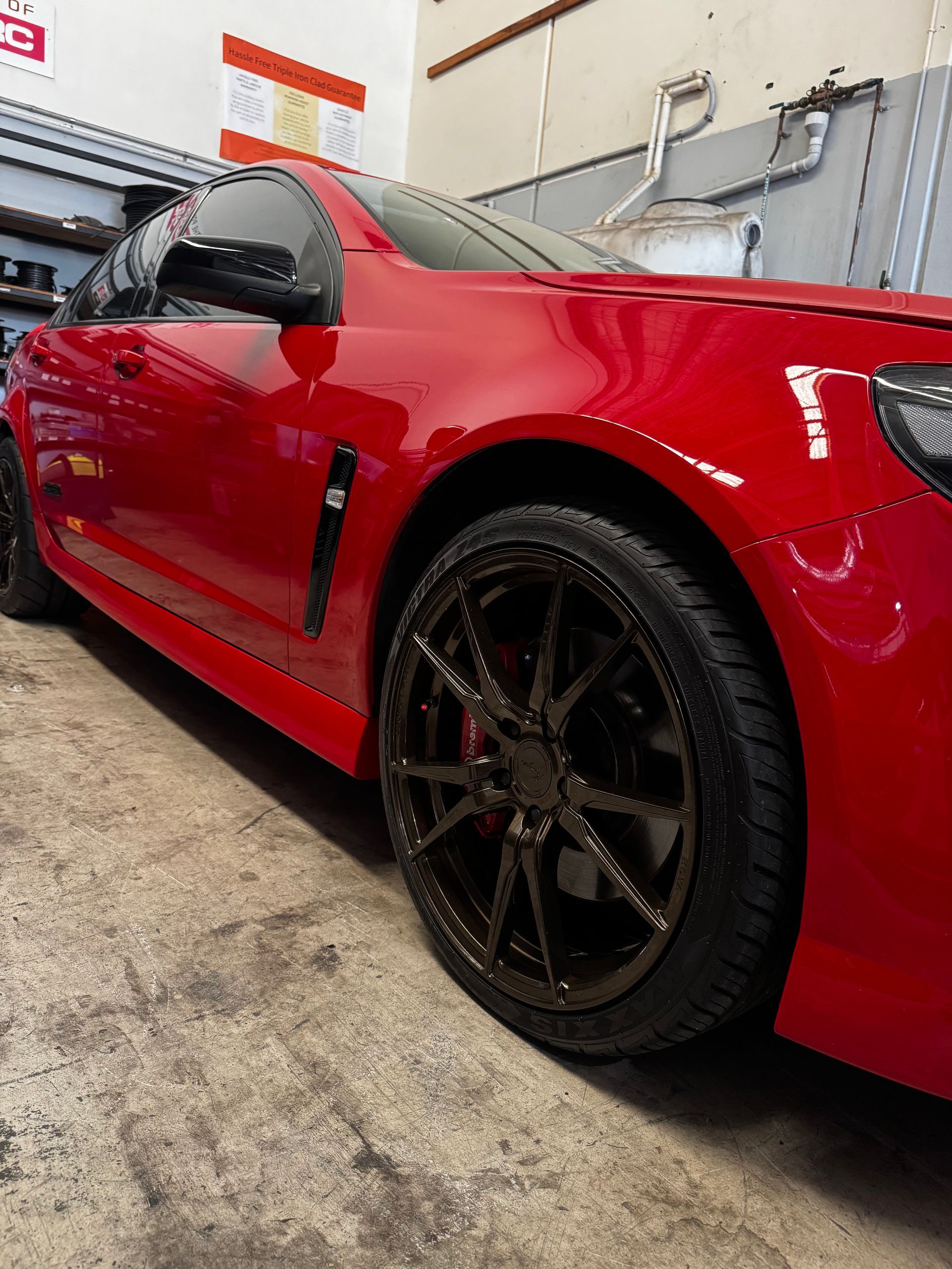 A Low-angle View Of A Shiny Red Sedan With Custom Dark Alloy — Elite Fleet Auto - Electrics & Mechanical in Cannonvale, QLD