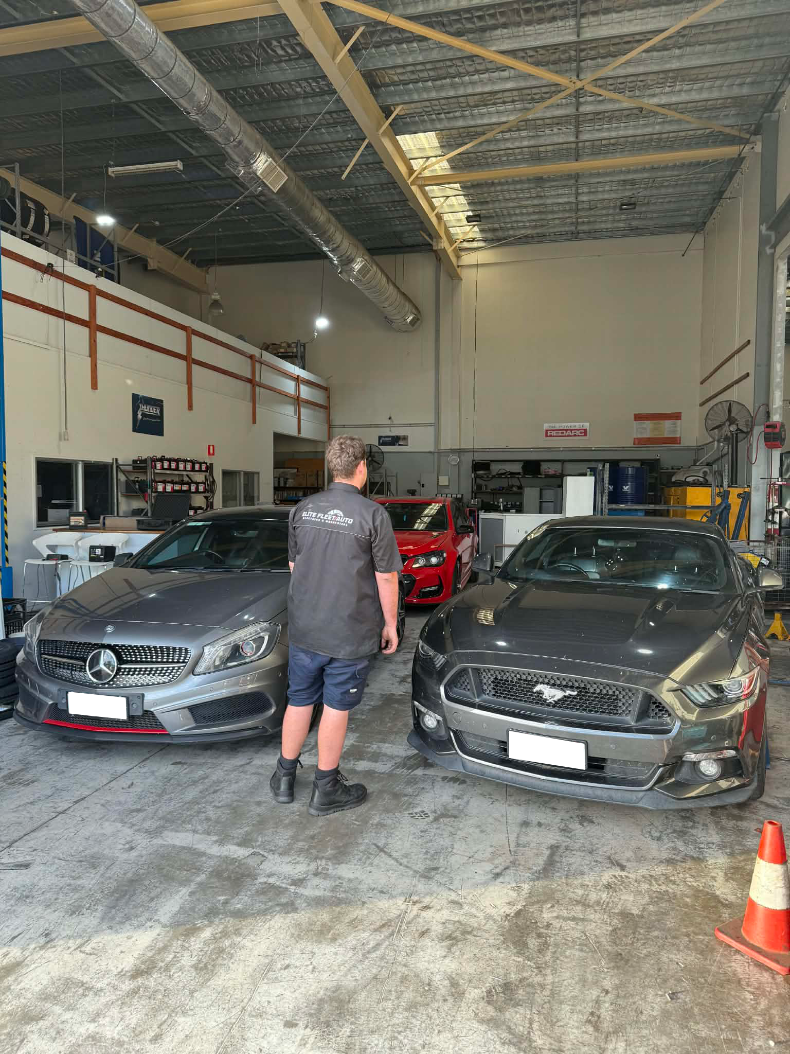 A Person Stands In A Workshop Between A Gray Mercedes-benz — Elite Fleet Auto - Electrics & Mechanical in Mackay, QLD