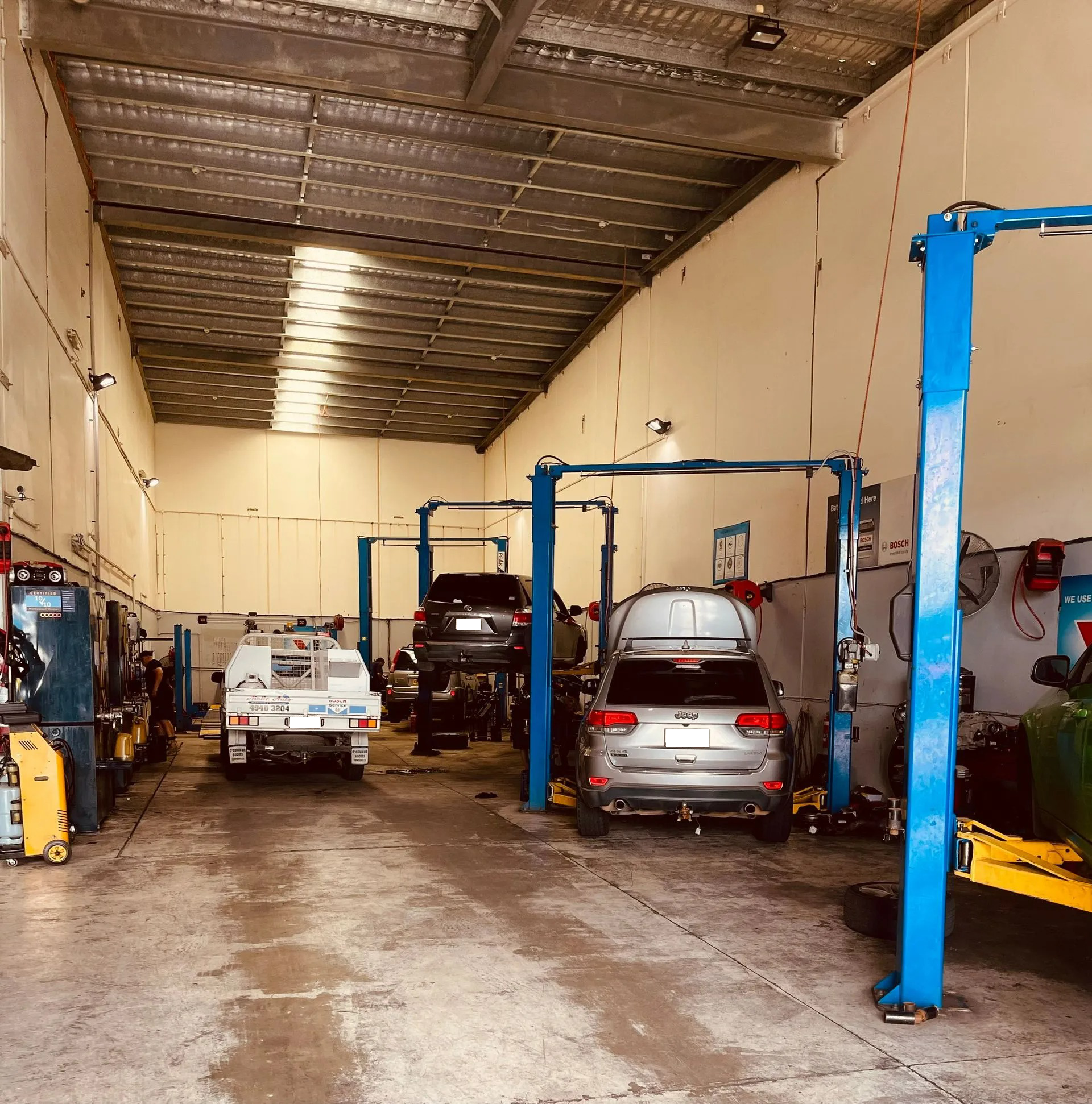 A Brightly Lit Auto Repair Workshop With Several Cars — Elite Fleet Auto - Electrics & Mechanical in Townsville, QLD