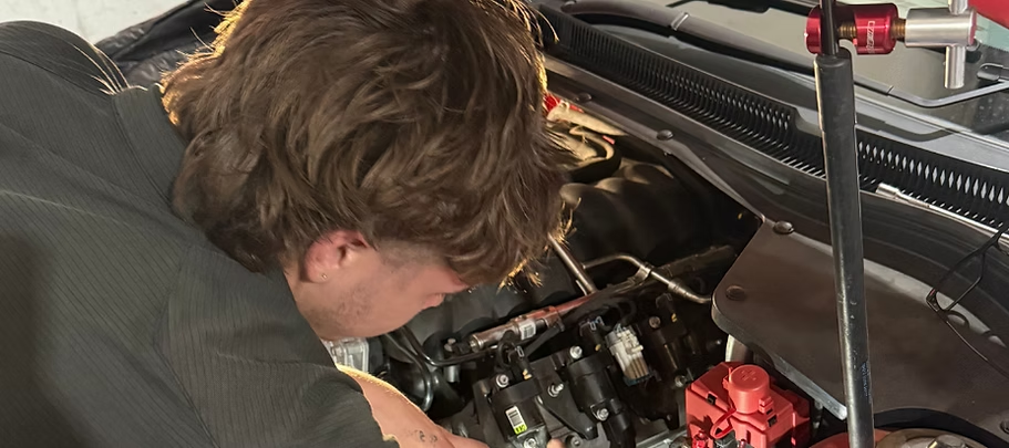 A Person Leans Over An Open Car Hood — Elite Fleet Auto - Electrics & Mechanical in Cannonvale, QLD
