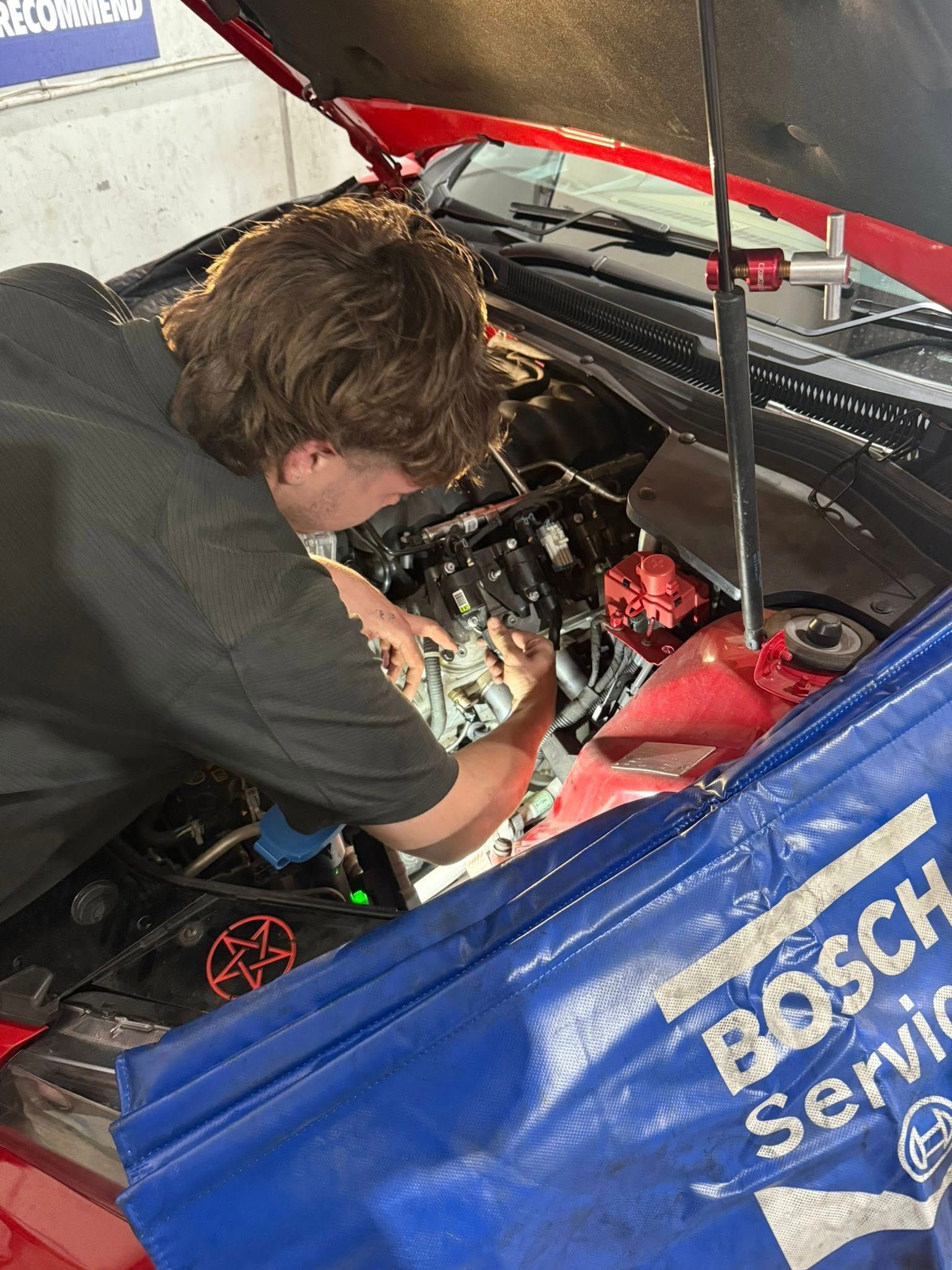 Mechanic Working on a Red Car's Engine Under the Hood in a Garage Setting — Elite Fleet Auto - Electrics & Mechanical in Cannonvale, QLD