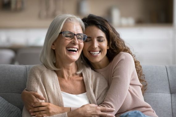A young woman is hugging an older woman on a couch.