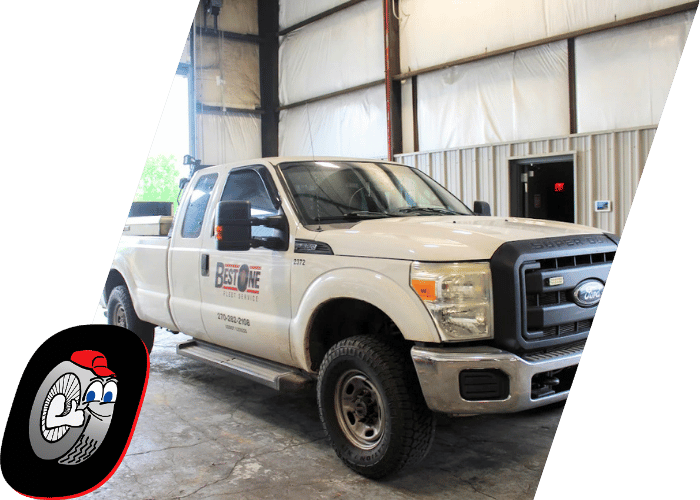 White Ford service truck parked inside a commercial truck repair facility.
