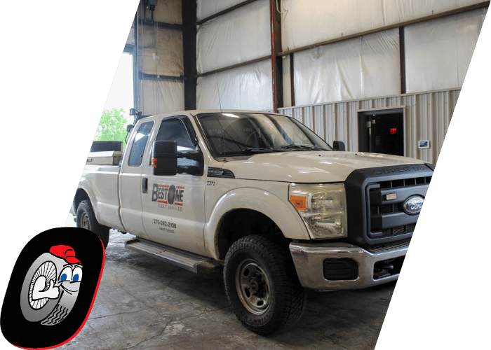 White Ford pickup truck parked inside a commercial fleet service facility.