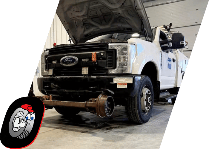 Heavy duty service truck undergoing repairs with the front axle removed inside the shop.