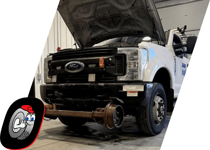 Heavy duty service truck undergoing repairs with the front axle removed inside the shop.