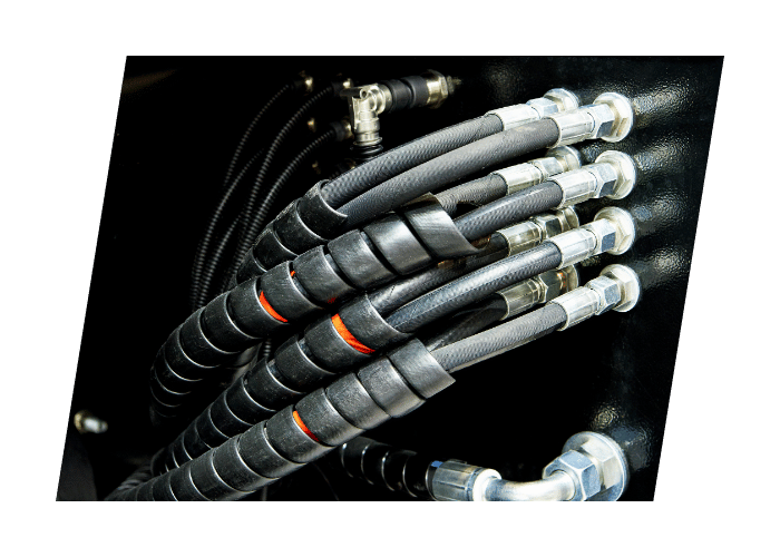 Close up of hydraulic hoses and fittings connected to industrial hydraulic equipment.