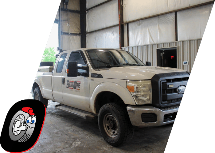 White Ford service truck parked inside a commercial truck repair facility.