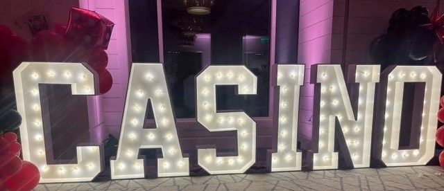 A large lighted marquee sign that says casino in a room with balloons.
