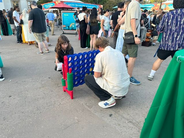 Connect Four game on a blue outdoor café table in a sunny courtyard