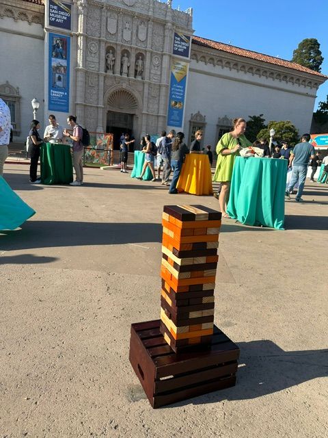 People playing giant Jenga outdoors around a table on a brick patio