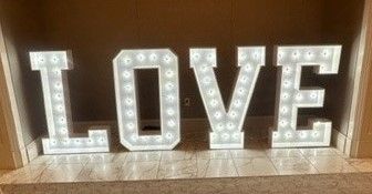 Illuminated marquee letters spelling “LOVE” on a mantel or shelf