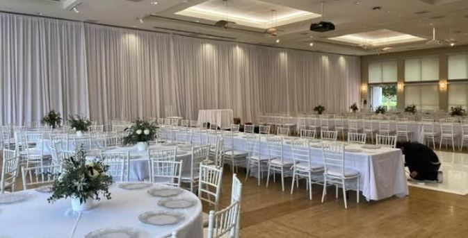 Elegant banquet hall with white chairs, long tables, and round tables set for an event