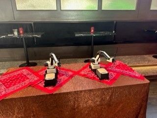 Two small robot figures on red scarves atop a table in a museum display