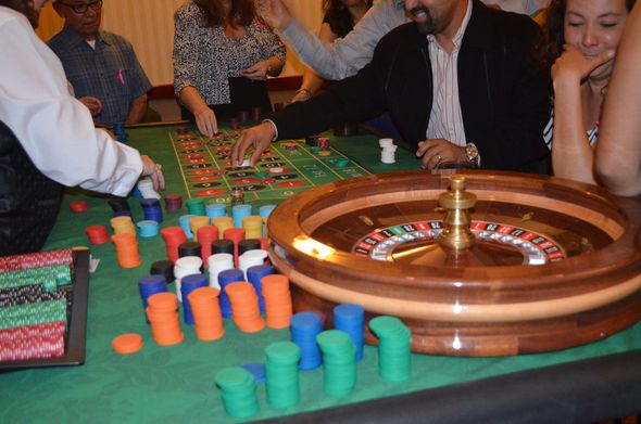 Casino roulette table with colorful chips and players gathered around it