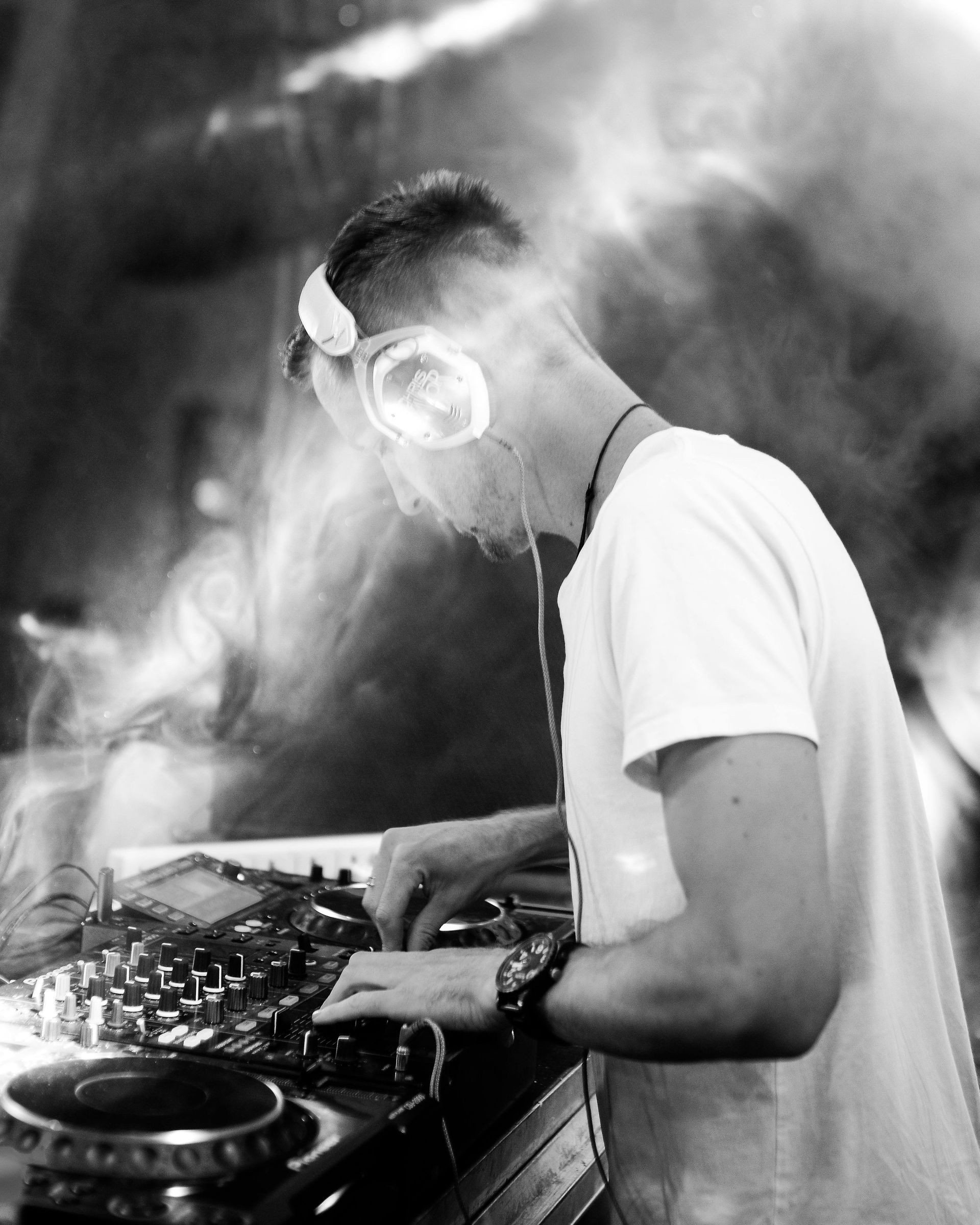 DJ wearing headphones mixing music at a turntable setup in a smoky club scene