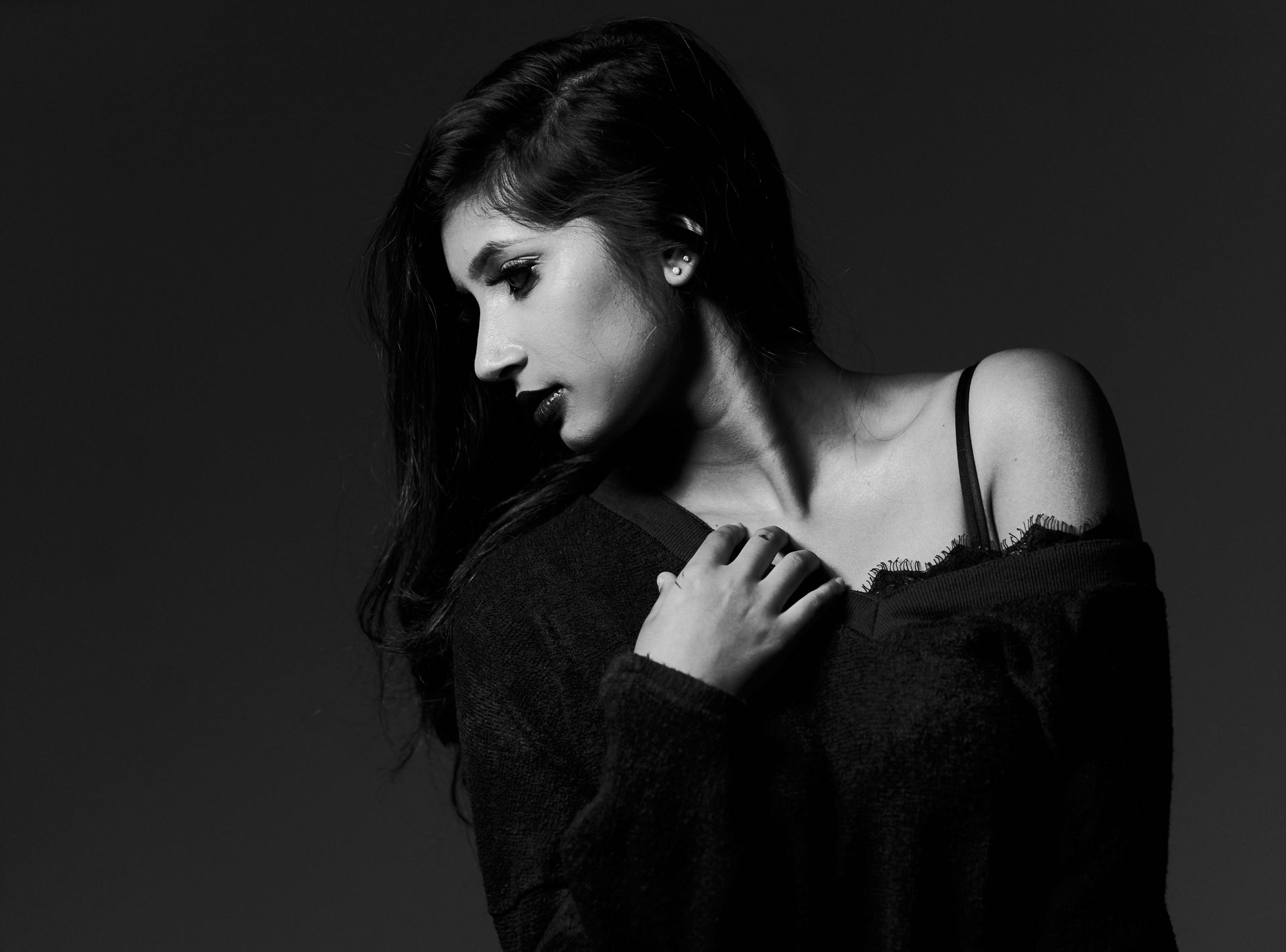 Black-and-white portrait of a woman with dark hair looking downward in a posed studio shot