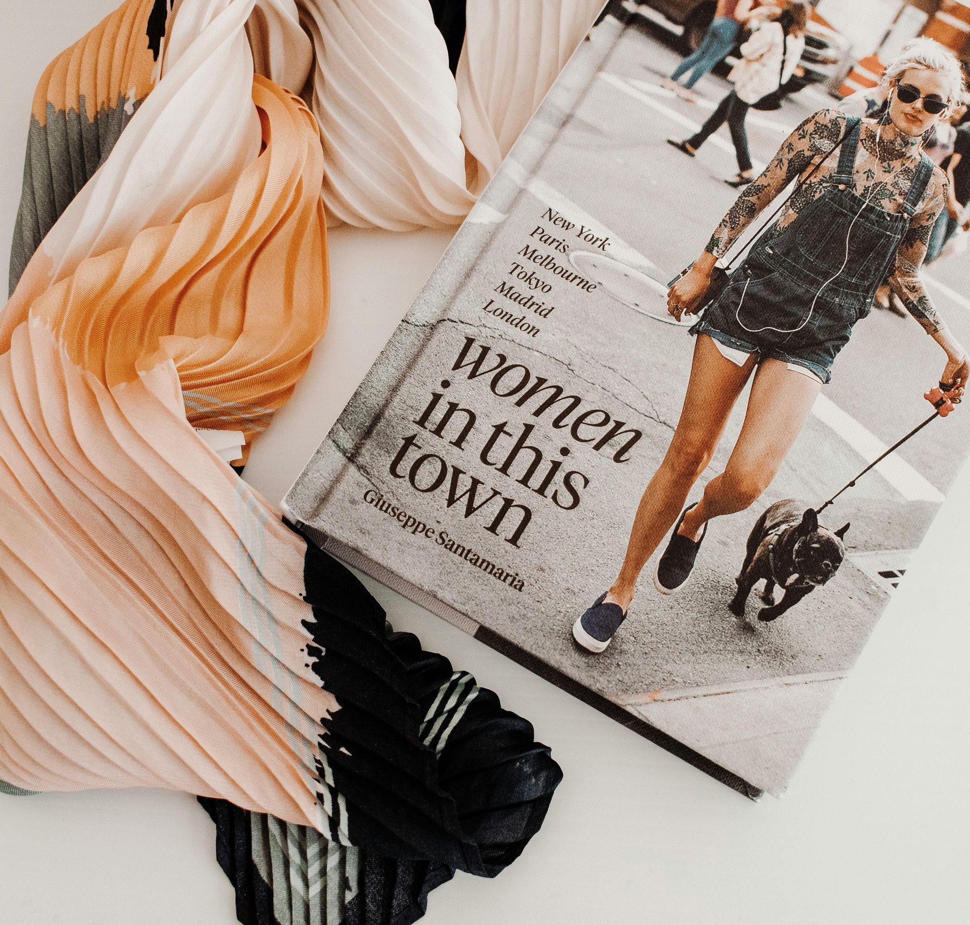 Magazine with “women in this town” cover beside orange, cream, and black folded clothes on a light surface