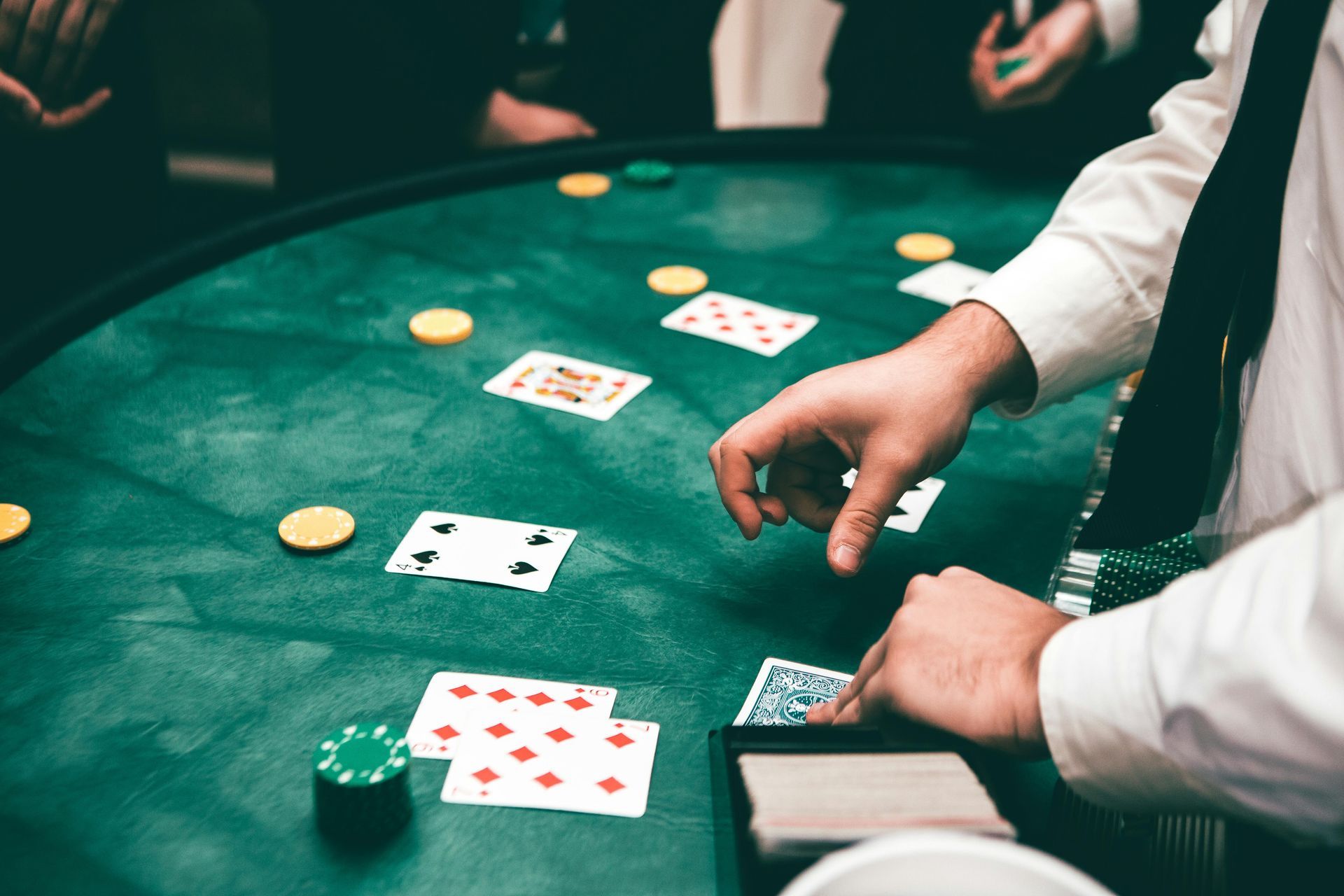 Hands deal cards at a green poker table with chips and cards scattered around.