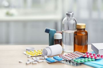 Verschiedene Medikamentenflaschen, Inhalatoren, Tabletten und Blisterpackungen auf einem Tisch in einer Apotheke oder Klinik