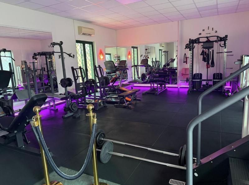 Palestra vuota con illuminazione a LED viola, macchine per i pesi e attrezzature per l'esercizio fisico.