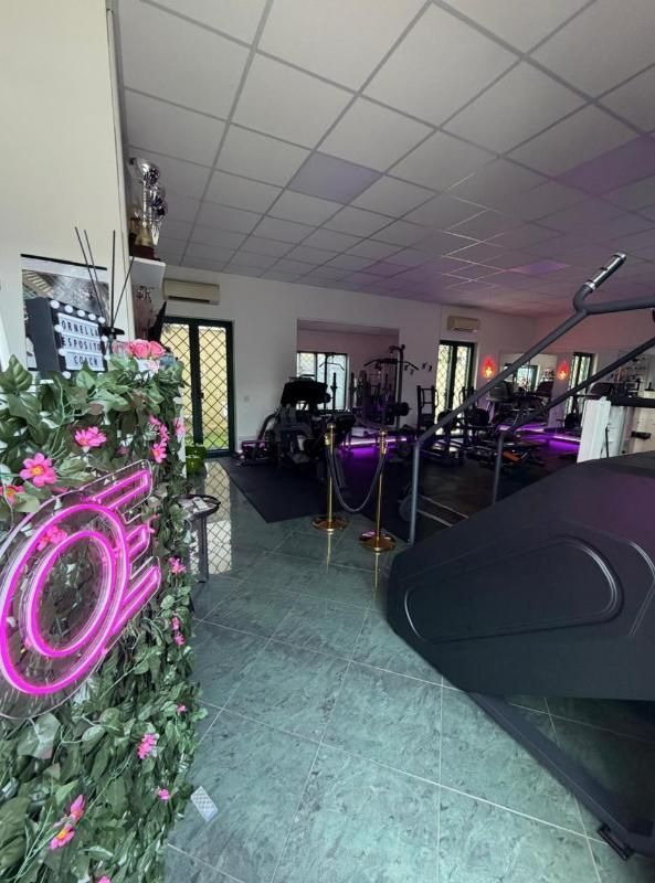 Interno di un salone da parrucchiere con insegna al neon rosa, poltrona da parrucchiere nera, specchi e decorazioni floreali.