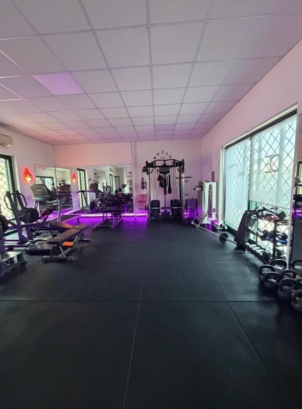 Palestra vuota con illuminazione viola, attrezzi ginnici e pavimento nero.
