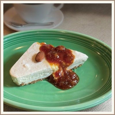 Slice of banana ice cream cake with caramel sauce and an almond on a green plate, with a coffee cup in the background.