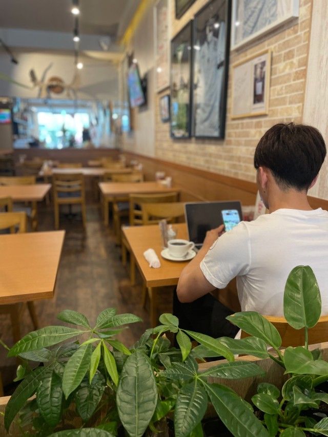 Café patron enjoying coffee while working on his laptop computer at a café in Nagoya, Japan.