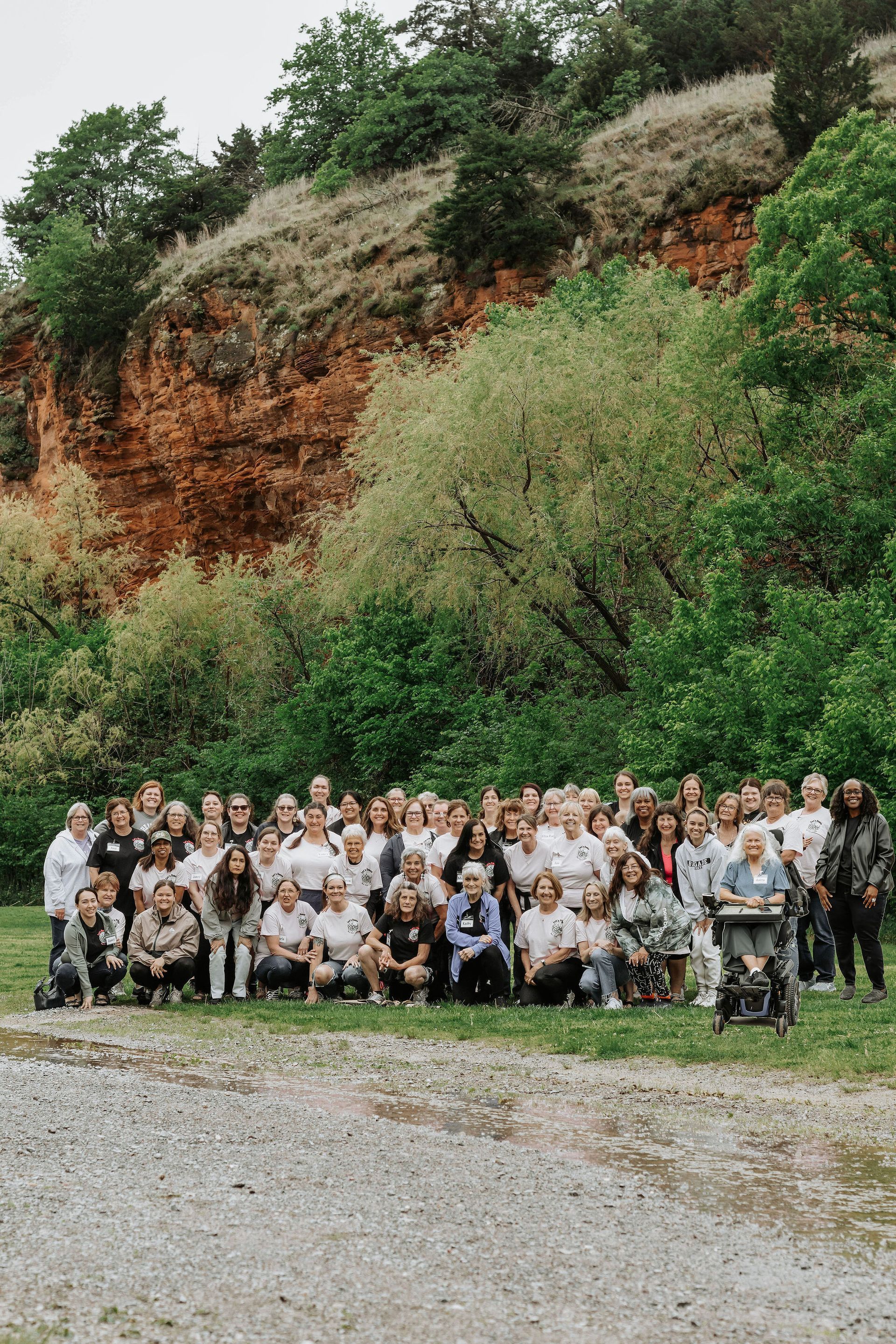 Group of people posing outdoors for a photo with a rock cliff in the background.