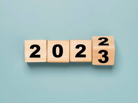The year 2023 is written on wooden blocks on a blue background.