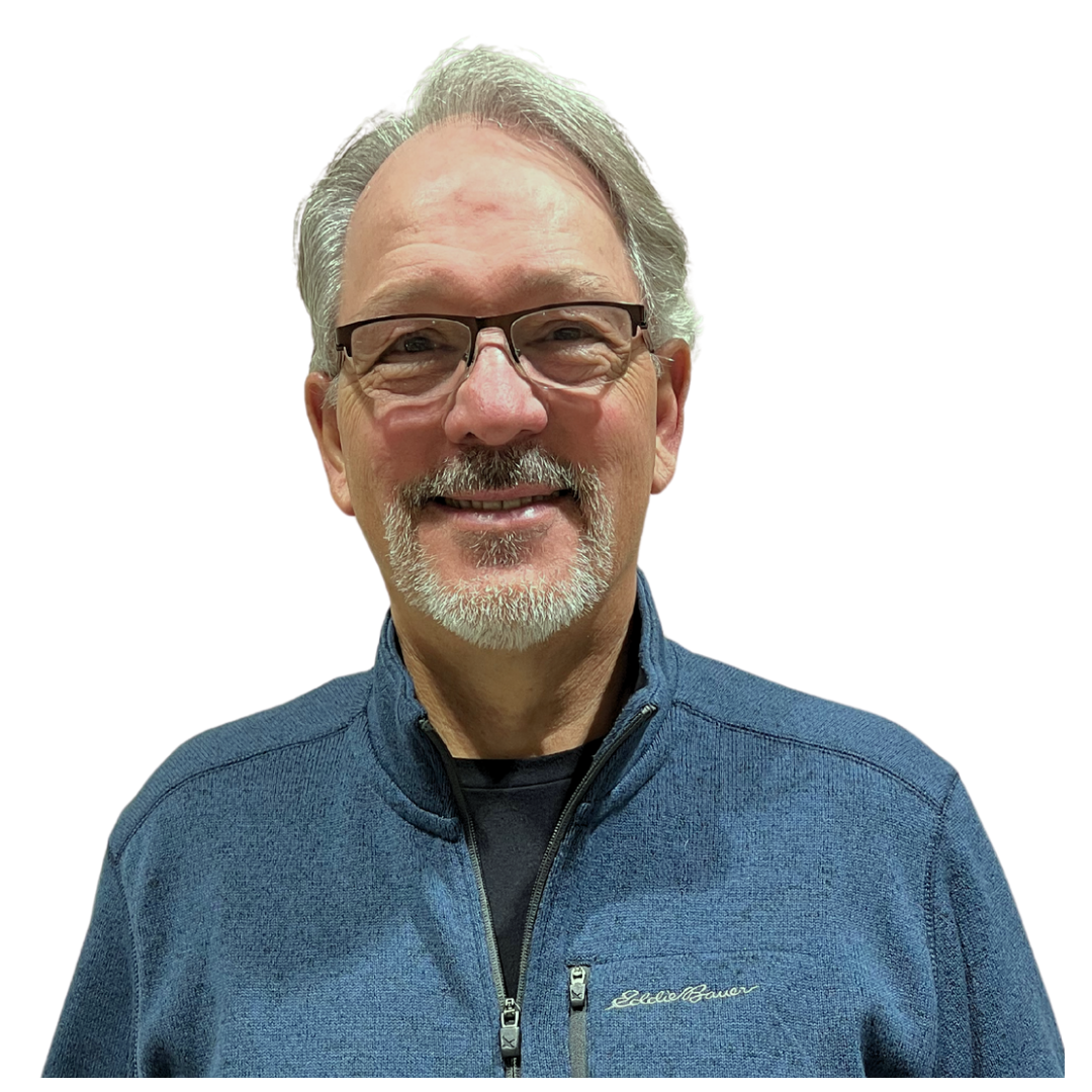 Smiling older man with glasses wearing a blue zip-up sweater.