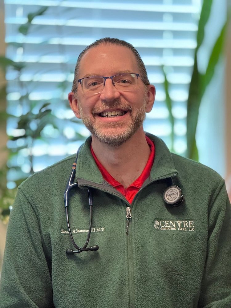 Dr Shannon with glasses and stethoscope, smiling, wearing a green jacket.