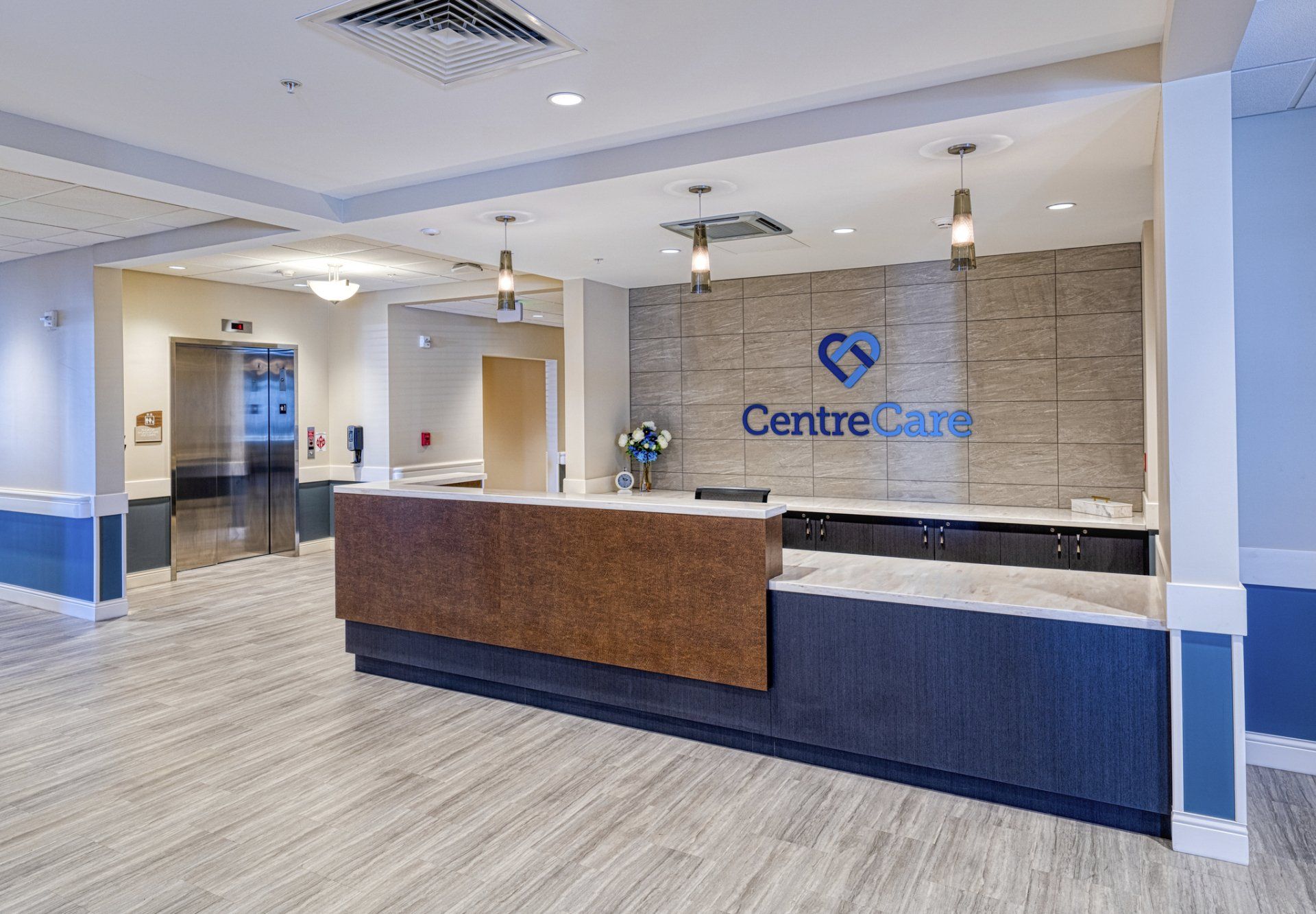 Reception area with CentreCare logo, elevators, and counter with blue and brown design.