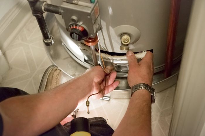 Man Shines Flashlight On Hot Water Heater - Torrington, WY - Midwest Plumbing, Inc.