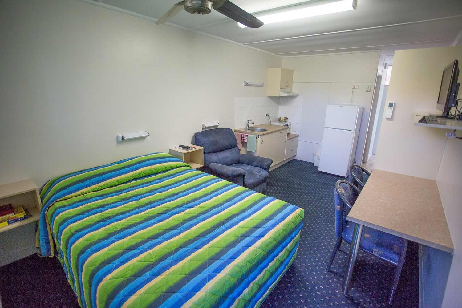 Small Motel Room With Bed, Desk, Kitchenette, Recliner, and Tv — Fourth Avenue Motor Inn in Parkside, QLD