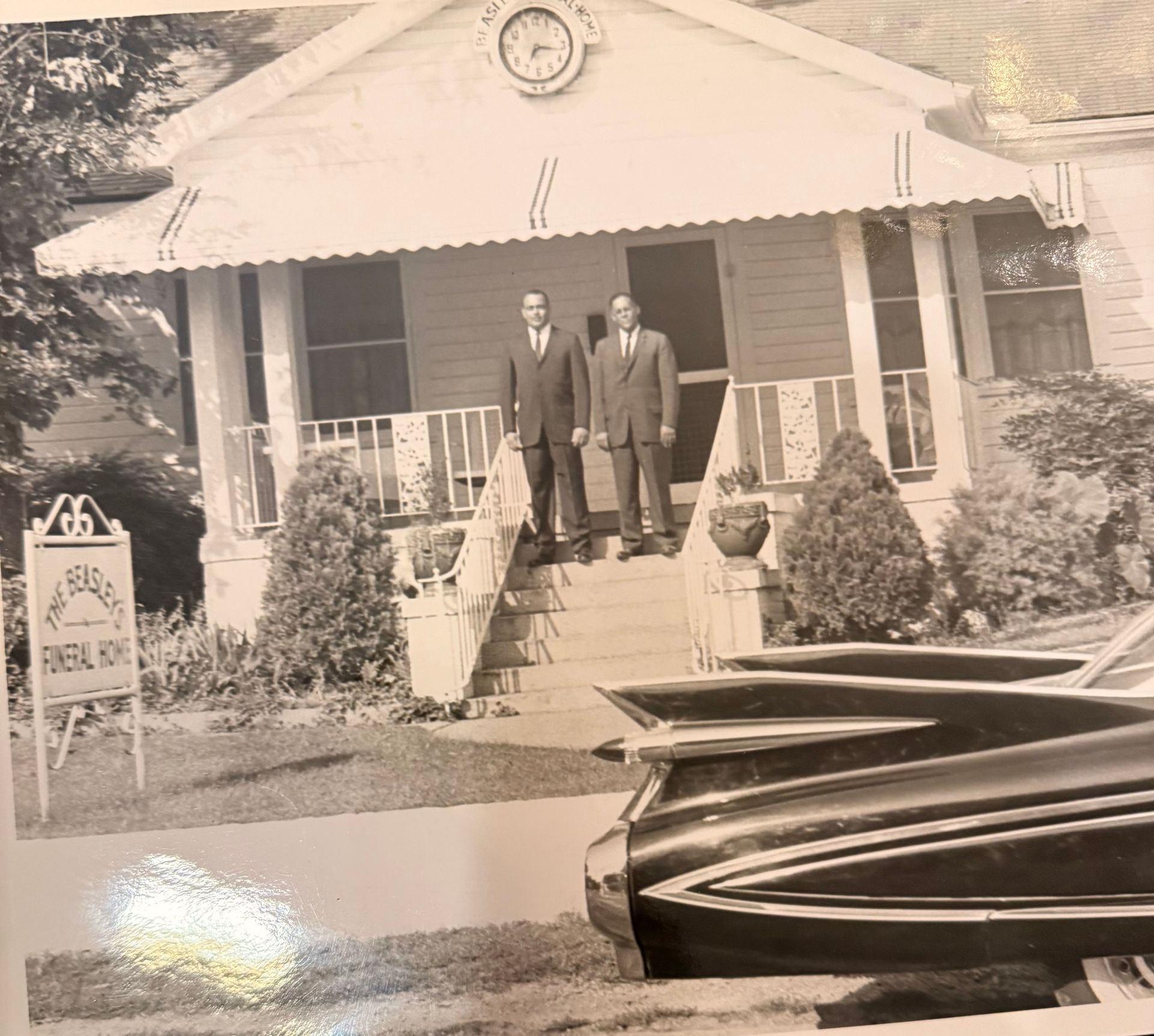 Two men standing on the steps of a small house with a boat in the foreground
