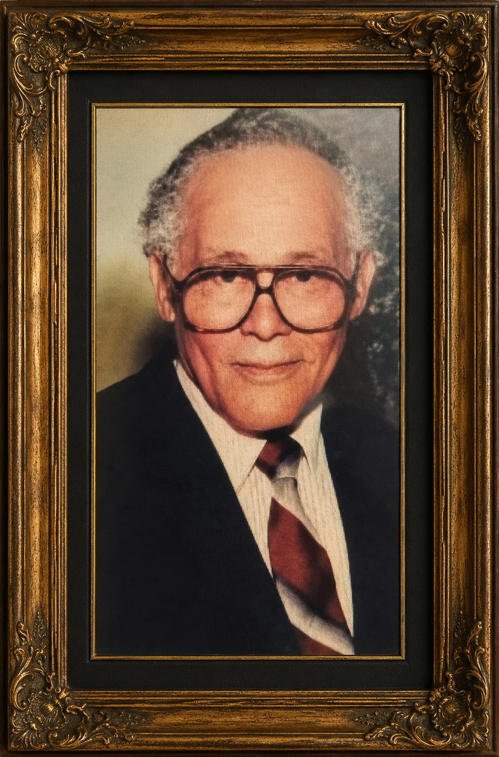 Framed portrait of an older man in glasses, wearing a dark suit and striped tie
