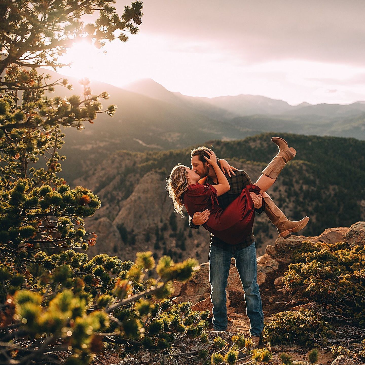 Man holding woman, kissing, mountain background, sunset.
