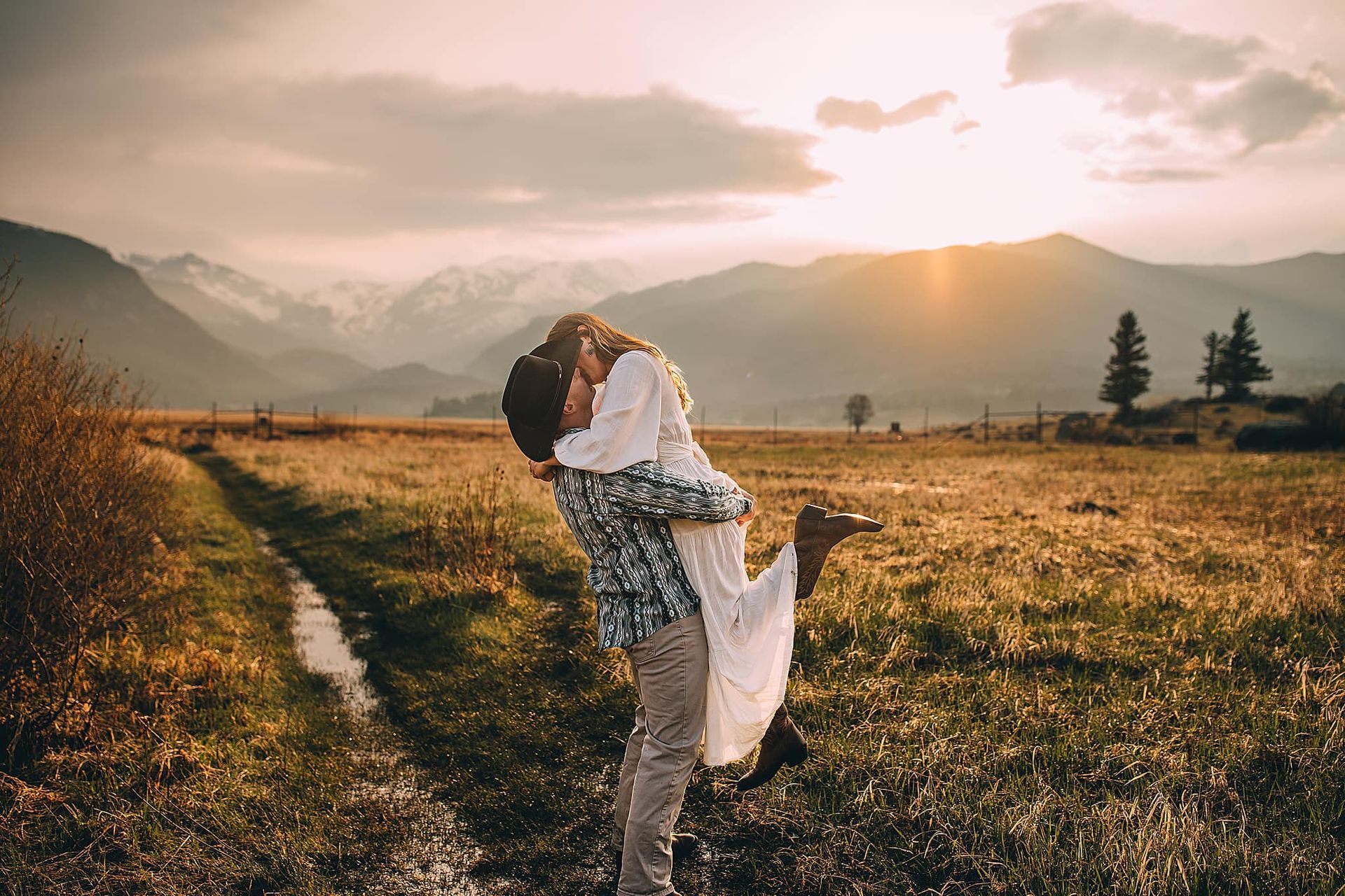 Man lifting woman in embrace in a field with mountains in background during sunset. Hudson Valley