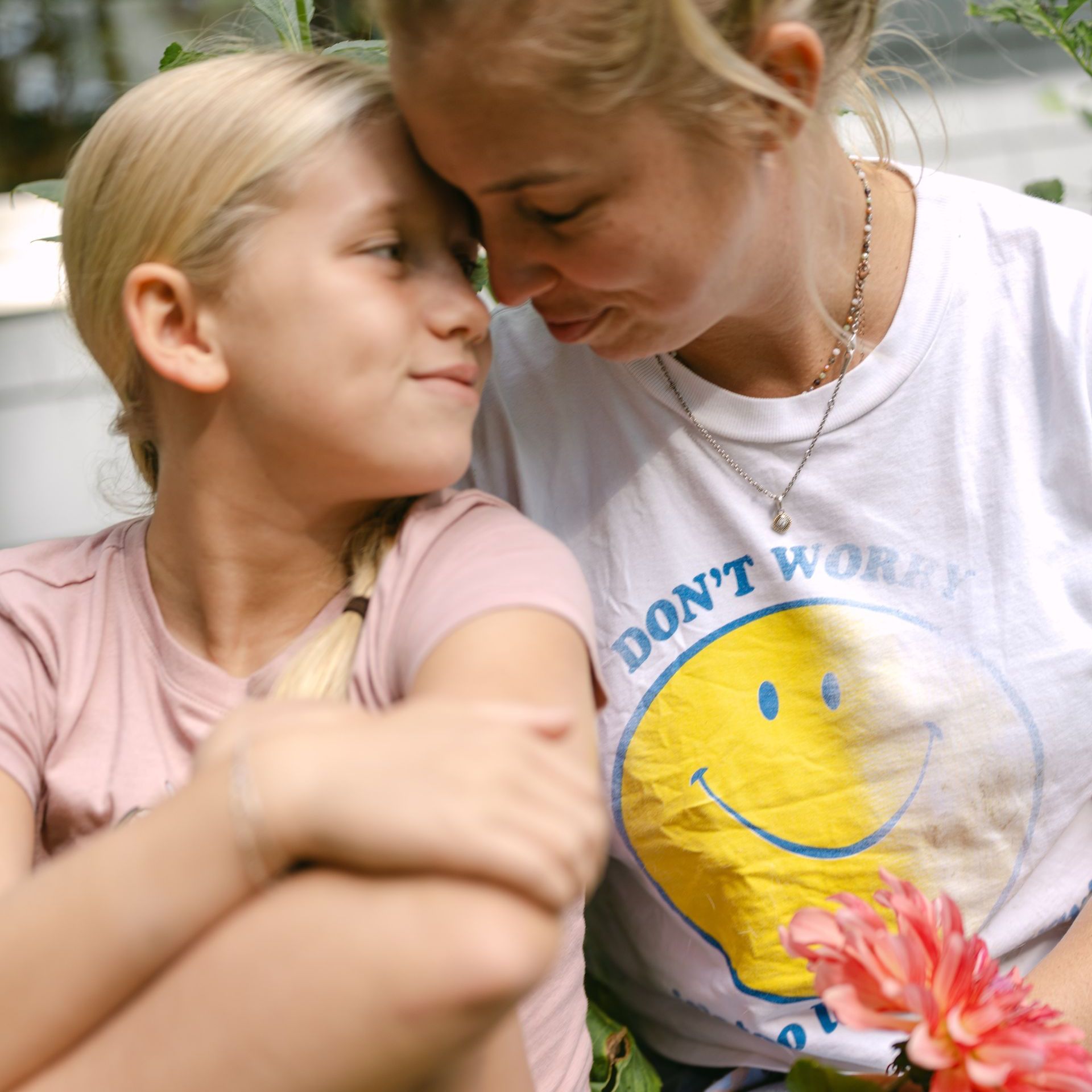 Woman and child with blond hair touching foreheads; woman's shirt says