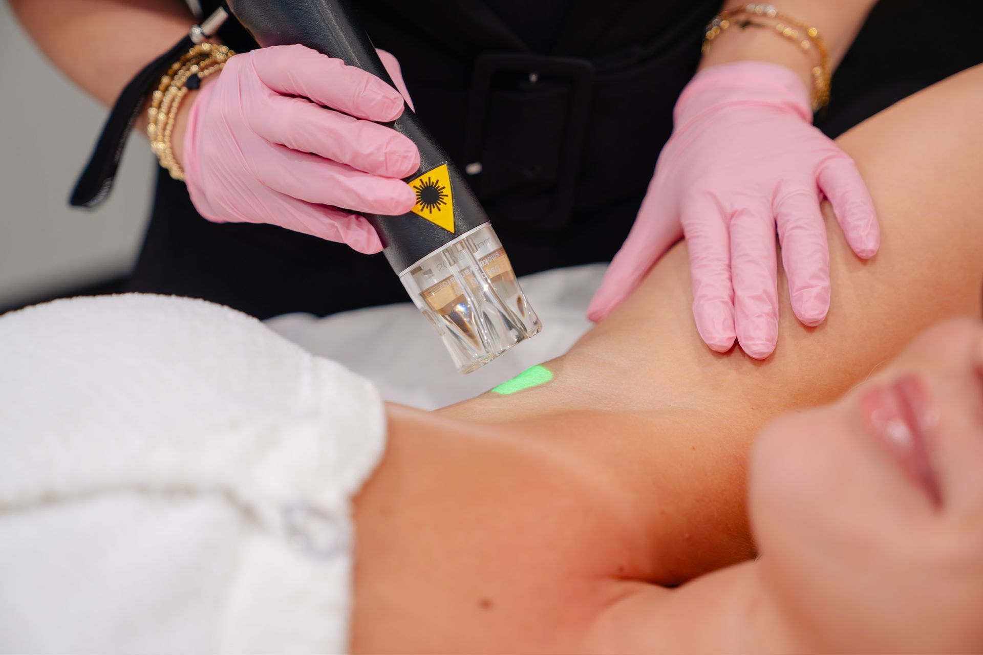 Gloved hands using a handheld device on a person’s chest in a spa or medical treatment setting