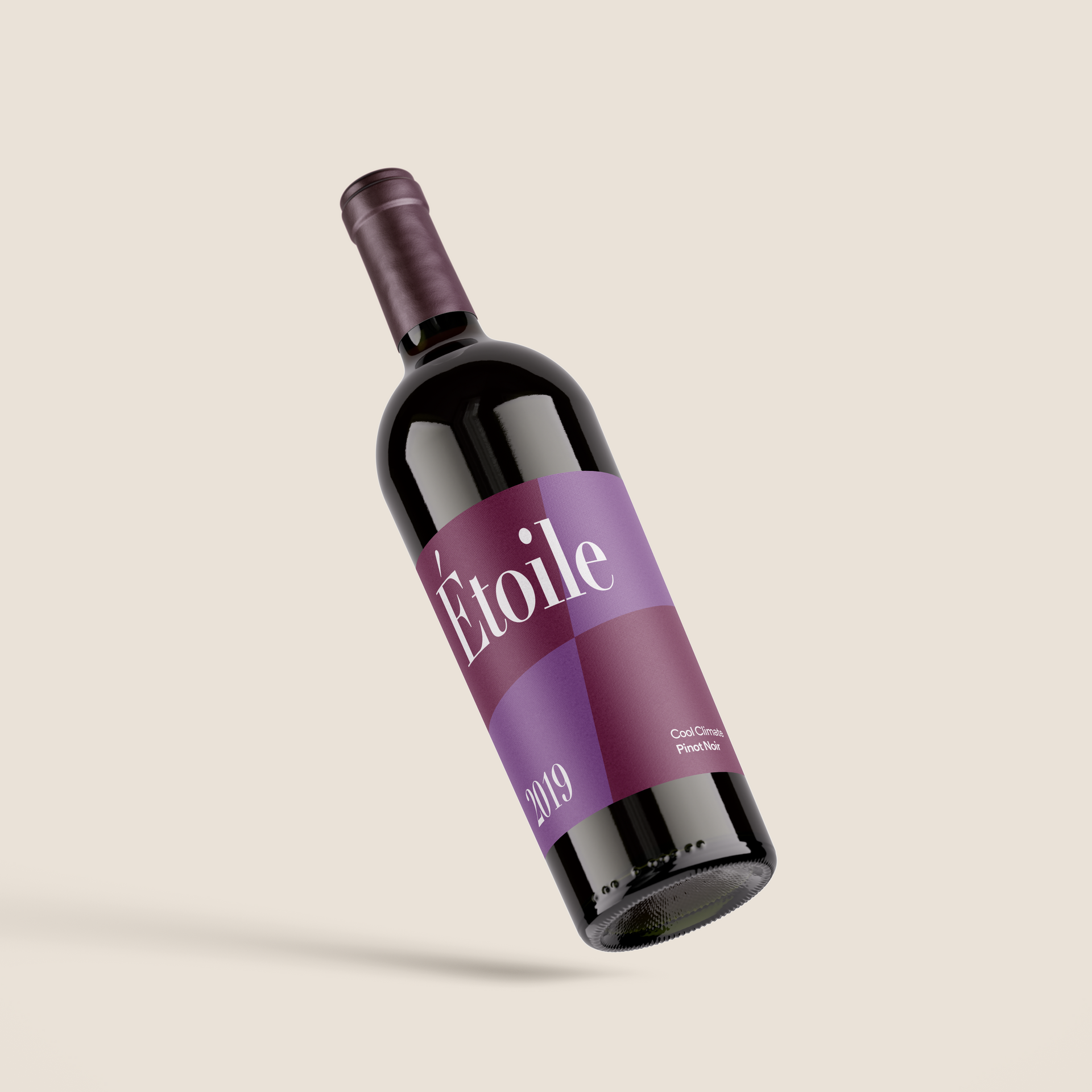 Garrafa de vinho roxa com o rótulo “Étoile” flutuando sobre um fundo bege.