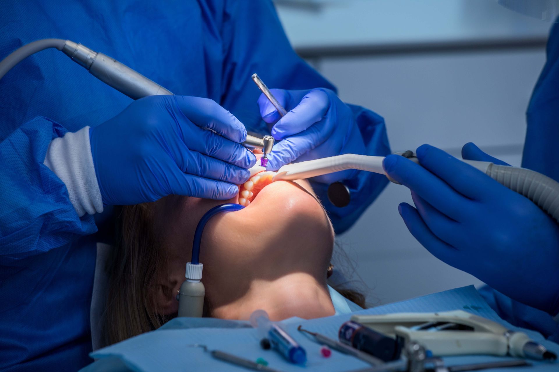 Un dentista esegue una procedura odontoiatrica su un paziente sotto una luce operatoria intensa.